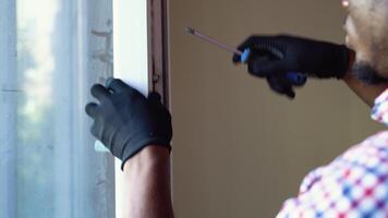 African american workman in overalls installing or adjusting plastic windows in the living room at home video