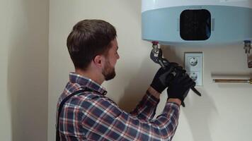 Professional plumber in uniform installing a boiler in new home video