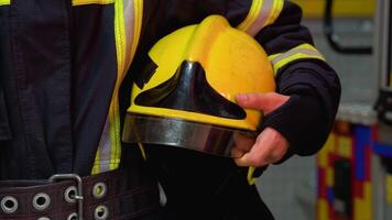 Firefighter with helmet in her hands standing at station, close up video