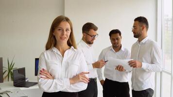 Smiling confident business leader looking at camera and standing in an office at team meeting video