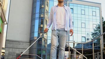 A blind man walking in city and using cane on pavement video