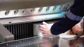 Worker cutting paper using paper cutting machine in a printing factory video