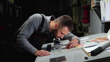 Worker in a printing press factory uses a magnifying glass and check the print quality video