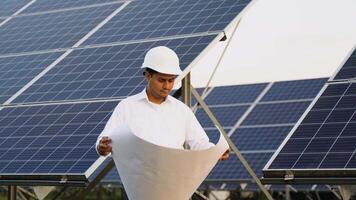Indian engineer in protective helmet checks technical documentation of the solar station after installation video