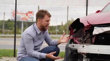 Upset man crying near a broken car after car crash video