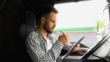 Delivery man with cardboard box checking list in truck. Courier sitting in truck and checking the delivery list video