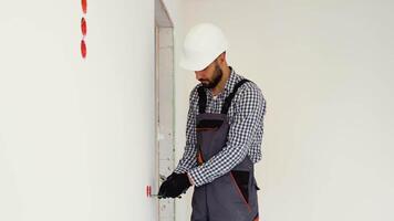 Electrician in uniform using pliers while replacing a socket in apartment after renovation work video