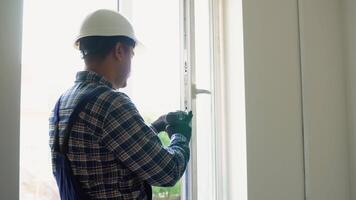 Indian workman in uniform installing or adjusting plastic windows in the living room at home video