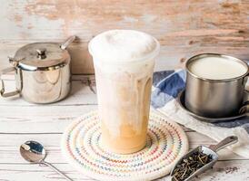 Iced Tieguanyin with Fresh Milk Tea or Tie guan yin with sugar pot and spoon served in disposable glass isolated on table side view of hong kong tea photo