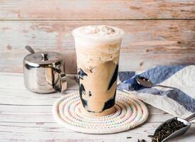 Iced Grass Jelly Milk Tea with sugar pot and spoon served in disposable glass isolated on table side view of hong kong tea photo