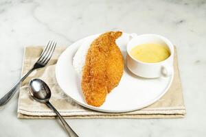 Crispy Fish Fillet with Rice in Sweet Corn Sauce with fork and spoon, served in dish isolated on napkin side view of asian food photo