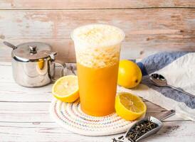Iced Emerald Lemon Tea or Pea Lemon Tea with sugar pot and spoon served in disposable glass isolated on table side view of hong kong tea photo