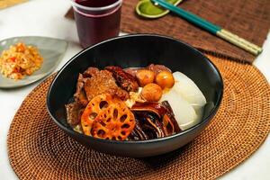 Signature lotus root Chowder Assorted Sides Noodle pot with drink and chopsticks served in pot isolated on napkin side view of japanese food photo