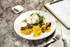 Porcini wontons with buffalo mozzarella and rocket, dip, fork and knife served in plate isolated on marble background side view of hong kong food photo