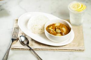 Nostalgic Curry Beef Brisket Rice with lemonade, fork and spoon, served in dish isolated on napkin side view of asian food photo