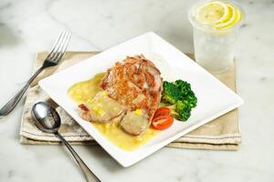 Crispy Chicken Steak with Rice in White Sauce with lemonade, fork and spoon, served in dish isolated on napkin side view of asian food photo