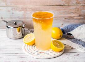 Iced lemon love jadeor or Lemon Aiyu tea with sugar pot and spoon served in disposable glass isolated on table side view of hong kong tea photo