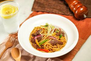 with lemonade, wooden spoon Spaghetti with Shredded Beef with Black Pepper and fork served in plate isolated on napkin and dining table side view of italian food photo
