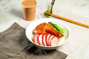 Chinese Sausage and Soya Chicken Leg with Rice with milk kopi chopsticks and spoon served in bowl isolated on napkin side view of hong kong food on marble background photo