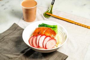 Chinese Sausage and Soya Chicken with Rice with milk kopi chopsticks and spoon served in bowl isolated on napkin side view of hong kong food on marble background photo