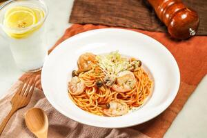 with lemonade, wooden spoon Spaghetti with Shrimps and mushroom in Italian Style and fork served in plate isolated on napkin and dining table side view of italian food photo
