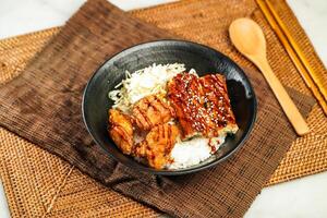 Grilled Eel with Deep Fried Shrimp Donburi with rice, chopsticks and spoon served in bowl isolated on napkin side view of Japanese food photo