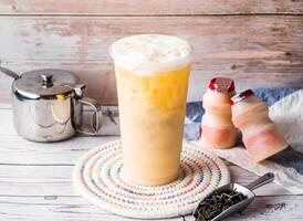 Iced Yakult green milk tea with sugar pot and spoon served in disposable glass isolated on table side view of hong kong tea photo
