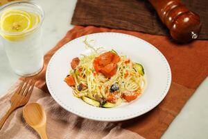 Linguine pasta with Crab Roe and Smoked Salmon in Japanese Style with lemonade, wooden spoon and fork served in plate isolated on napkin and dining table side view of italian food photo