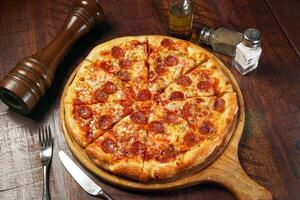Signature Pepperonis Special Pizza isolated on cutting board top view on table italian fastfood photo