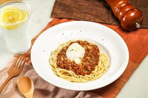 Wagyu Beef Bolognese with Soft Boiled Egg with lemonade, wooden spoon and fork served in plate isolated on napkin and dining table side view of italian food photo