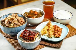 Assorted japanese food verity Teriyaki eel donburi with rice, UMAI Beef Donburi, Deep Fried Chicken and Deep Fried Shrimp Curry rice, and iced tea served on table side view of asian food photo