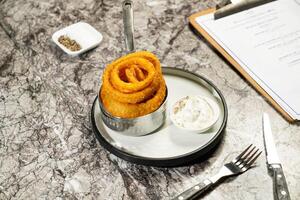 Crispy Onion Rings with Tartar Sauce, fork and knife served in plate isolated on marble background side view of hong kong food photo
