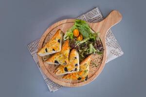 Black truffle toast with garden salad served in wooden board isolated on napkin top view of chinese food on grey background photo