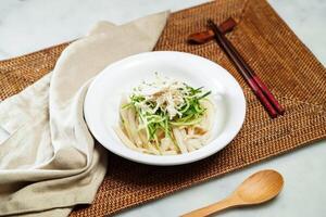 Sesame Sauce Cucumber Shredded Chicken Vermicelli with chopsticks and spoon served in bowl isolated on napkin side view of Chinese food photo