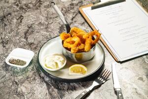 Crispy Squid Calamari Rings with Japanese Wasabi Mayonnaise dip, fork and knife served in plate isolated on marble background side view of hong kong food photo