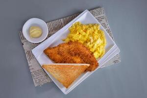 Crispy fried fish fillet, Smooth milk scrambled eggs and Butter toast served in dish isolated on napkin top view of chinese food on grey background photo