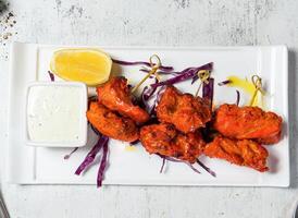 Tandoori Chicken Skewers tikka boti kabab with lemon and sauce dip served in plate isolated on background top view of italian food photo