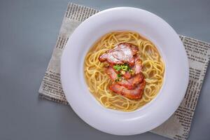 Nostalgic barbecued pork soup and spaghetti served in dish isolated on napkin top view of chinese food on grey background photo