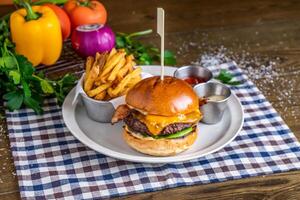 Brewers Burger with beef, french fries, ketchup, mayo dip, tomato, onion, capsicum, coriander, served in dish isolated on napkin side view of italian fastfood on wooden table photo