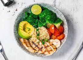 Grilled Chicken Breast Bowl with broccoli, corn, lettuce, fried rice and lemon served in bowl isolated on background top view of italian food photo