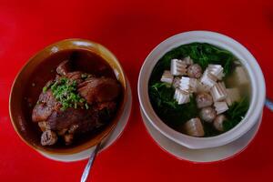Pork Shank with Steamed Chinese Buns in a bowl and Clear soup with bean curd and minced pork boiled with vegetable in a bowl. Tradition food in Thailand photo