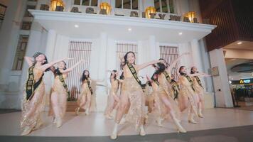 A dynamic group of dancers performing in a mall, wearing golden costumes and striking synchronized poses, showcasing energy video