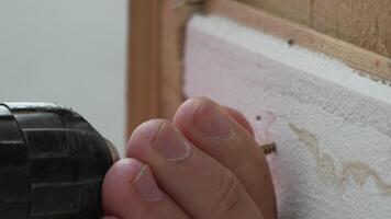 A man hands using a power tool fastens a board with a screw. Slow motion video