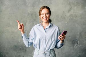 Cheerful young woman with a smartphone, enthusiastically showcasing a mobile app. Perfect for business, tech, or app promotion imagery. Isolated on a neutral background. Ideal for ads and web services photo