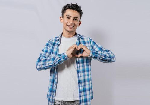 Smiling guy making heart shape with hands isolated. Happy man making heart shape with hands isolated. Person putting hands together in a heart shape photo