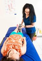 Woman physiotherapist using vibration gun to relieve muscle pain, Physiotherapist using massage gun on female patient. Chiropractor using massage gun on female patient photo