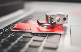 Concept of theft of information on credit cards. Padlock on top of credit card on laptop keyboard, Open padlock with credit card on keyboard photo
