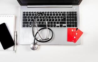 Stethoscope with credit cards on keyboard. Stethoscope on laptop keyboard with credit cards photo