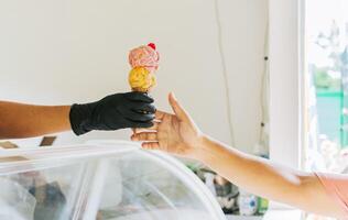 Close-up of hands buying an ice cream. Close up of hands receiving an ice cream cone. Close up of person buying an ice cream cone photo