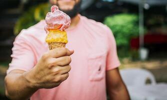 Front view of person hands holding an ice cream cone. Unrecognizable people holding ice cream in cone outdoors. People showing a double ice cream cone. Cone ball ice cream concept photo